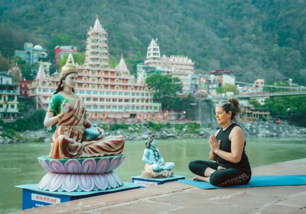 elderly woman meditating in front of a statue of parvati on the ganges